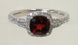 A vibrant 6mm cushion-cut garnet blazes at the center, encircled by a halo of dazzling diamonds.